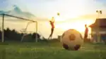 Fotboll med mål och två spelare i bakgrunden